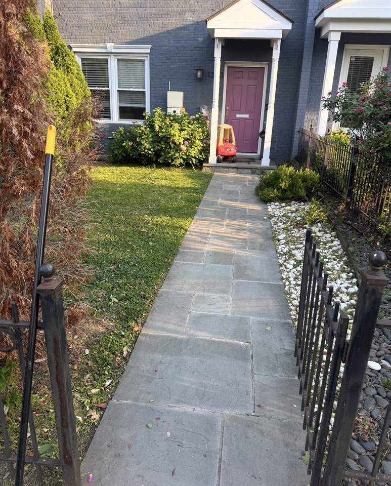 Trimmed front lawn and clean flagstone walkway leading to a front door
